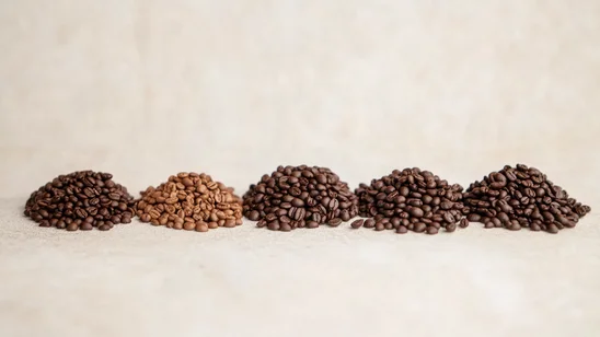 خمسة أكوام من حبوب القهوة المحمصة بدرجات مختلفة، من الفاتح إلى الغامق، لعرض الفروق بين أنواع الحمصة المختلفة